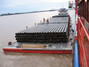 Charter ship discharging pipe onto barge for project